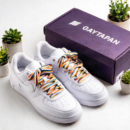 Lacets aroace orange, blanc et bleus lacés sur des baskets blanches, à côté d'une boîte GAYTAPAN