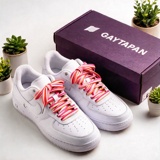 Lacets lesbiens orange, blanc et roses lacés sur des baskets blanches, à côté d'une boîte GAYTAPAN