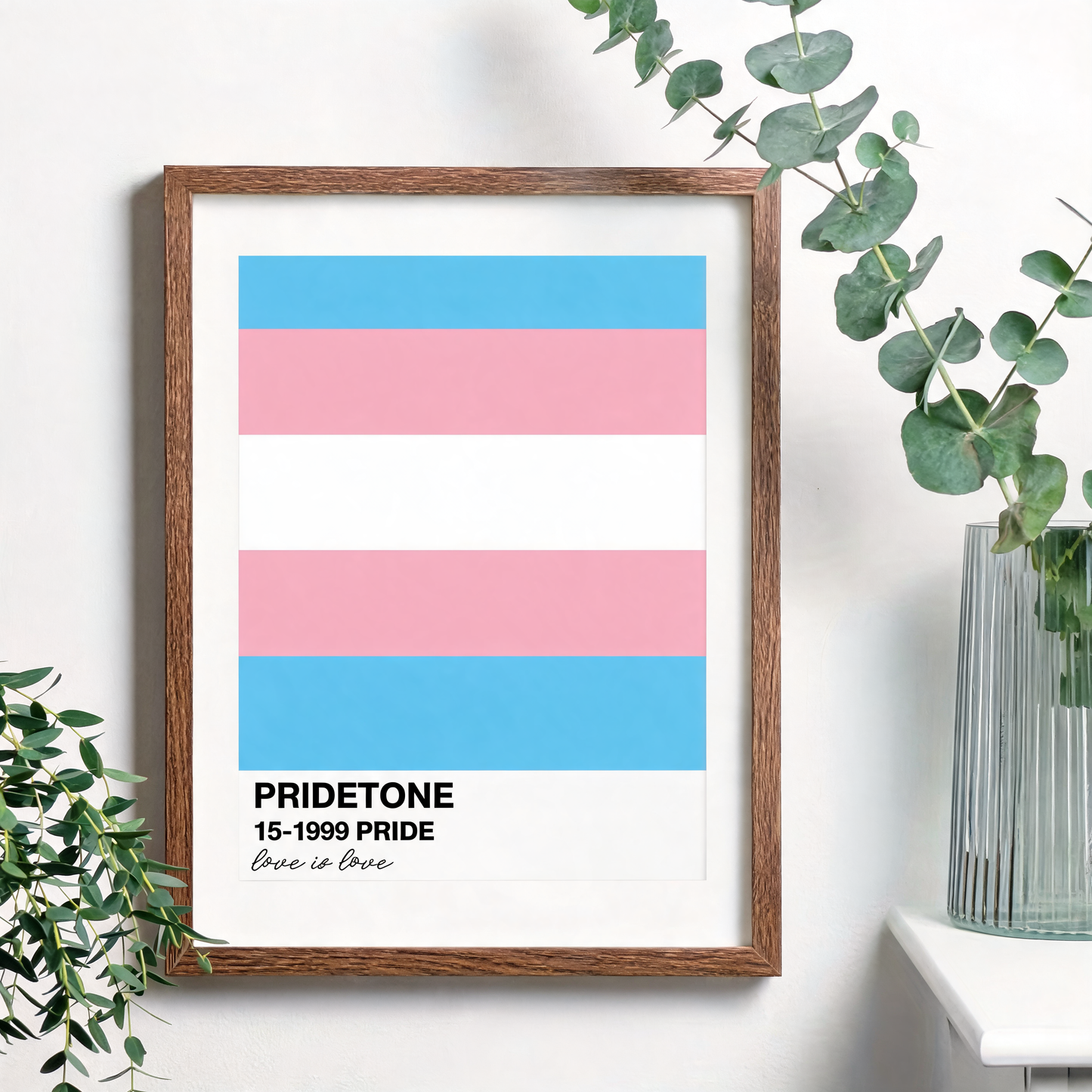 Affiche du drapeau transgenre en nuancier Pride, bleu ciel, rose et blanc, dans un cadre bois non inclus sur un mur blanc