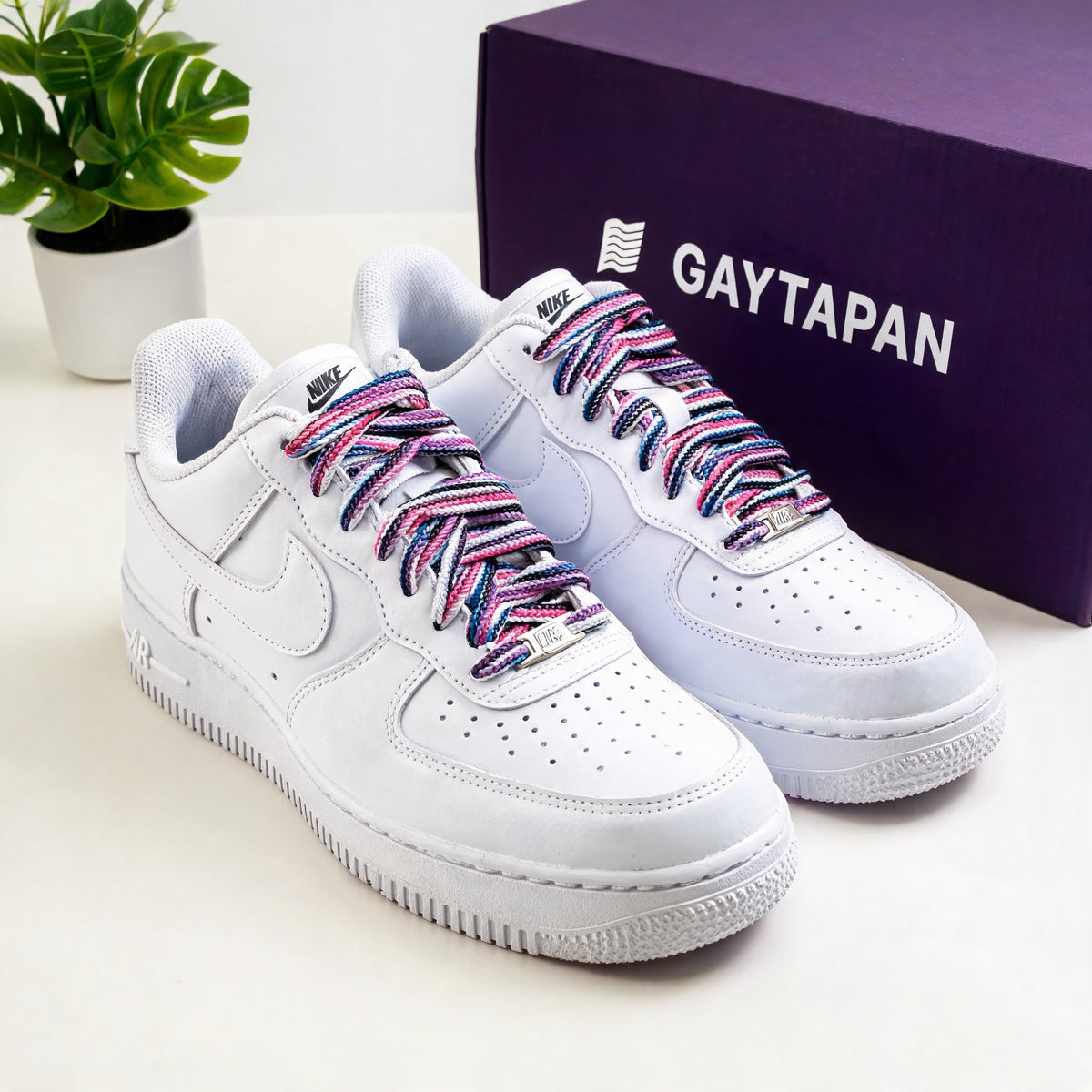 Lacets genderfluid rose, blanc, magenta, noir et bleu lacés sur des baskets blanches, boîte GAYTAPAN