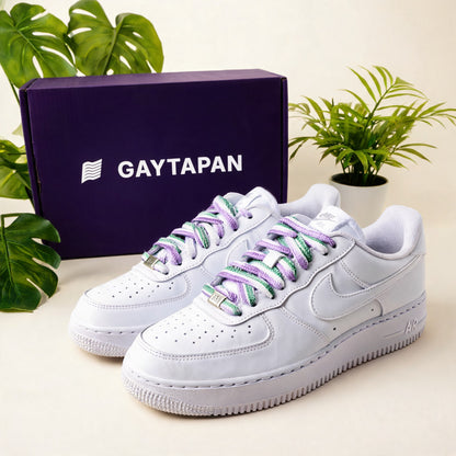 Lacets genderqueer lavande, blanc et vert lacés sur des baskets blanches, boîte GAYTAPAN à l'arrière-plan