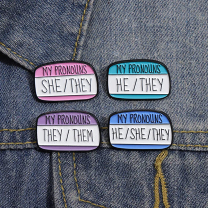 Quatre pins pronoms épinglés sur une veste en jean