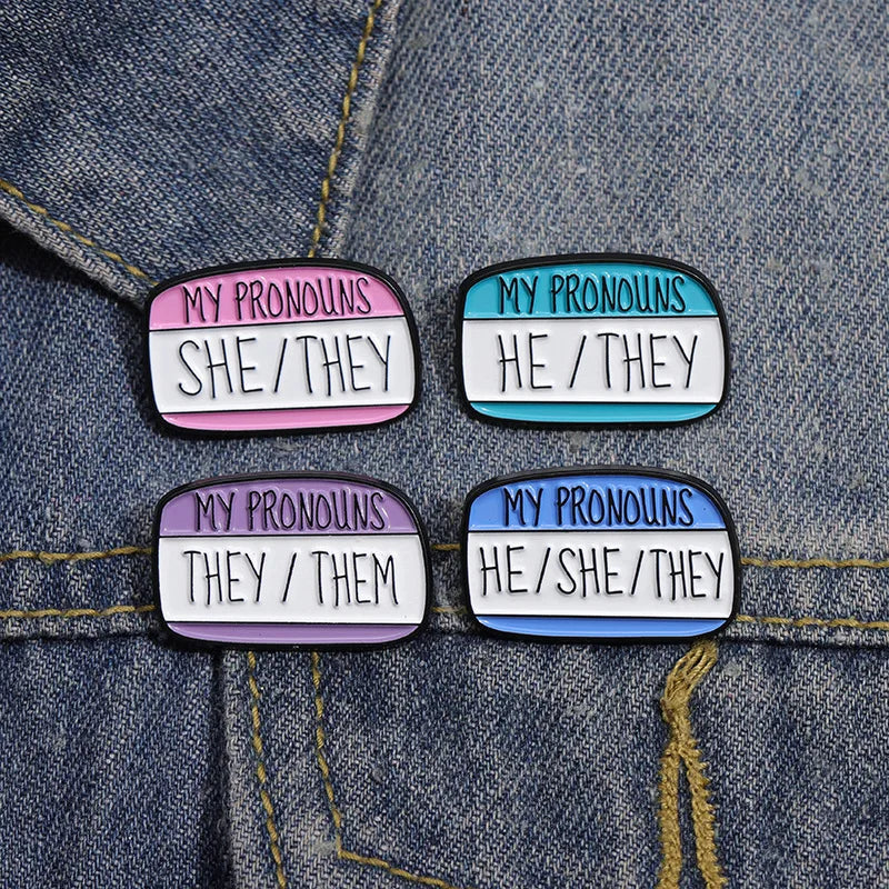 Quatre pins pronoms épinglés sur une veste en jean