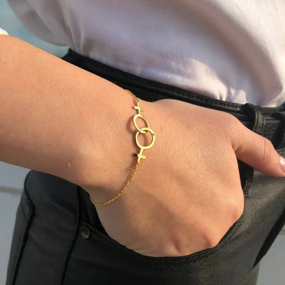 Bracelet lesbien double Vénus doré porté au poignet, main dans la poche