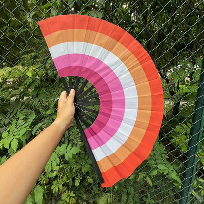 Éventail au drapeau lesbien tenu à la main et déplié — dégradé orange, blanc et rose