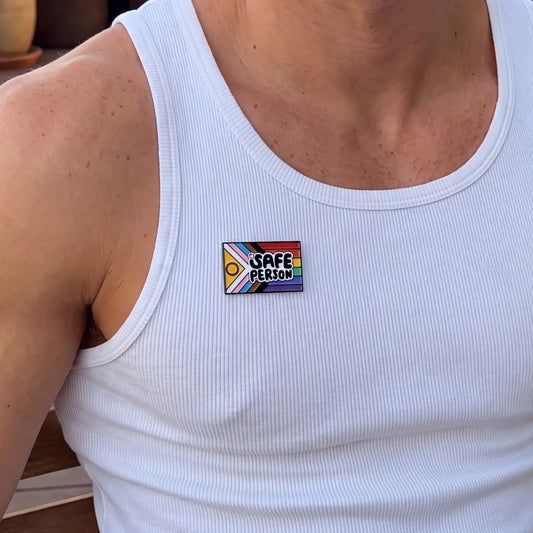 Homme portant le pins LGBTQIA+ Safe Person sur un débardeur blanc