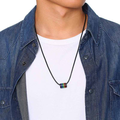 Le collier cylindre arc-en-ciel porté par un homme, sous une chemise en jean ouverte