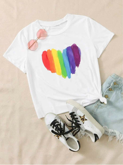 Le t-shirt au cœur arc-en-ciel posé à plat avec un jean et des baskets